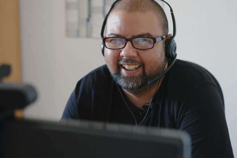 Ein Mann sitzt mit Kopfhörern vor einem Bildschirm