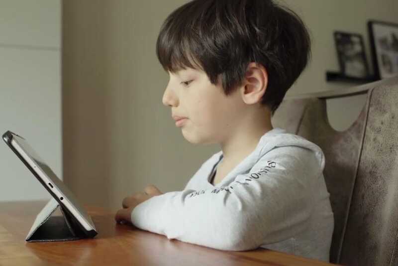 Ein Kind sitzt vor einem Tablet und schaut interessiert drauf