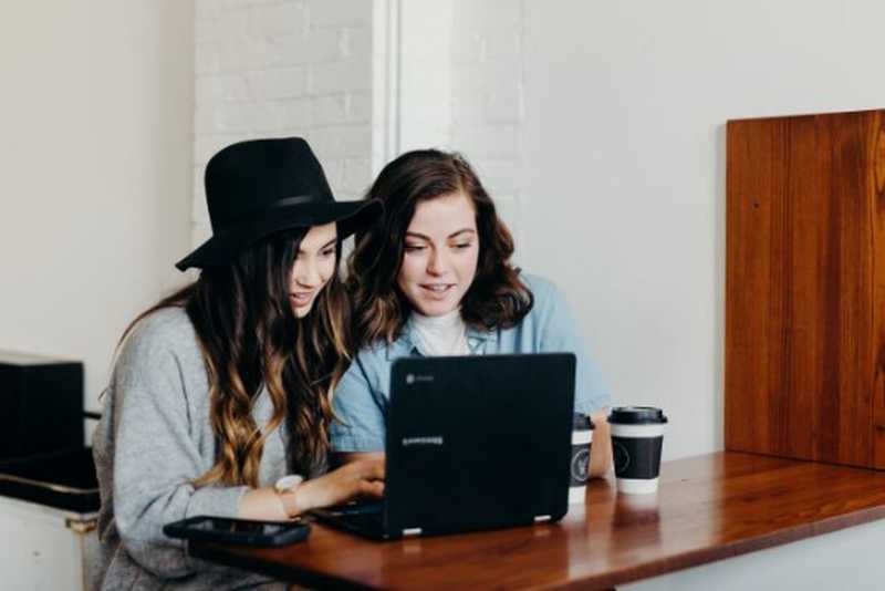 Zwei Frauen sitzen vor einem Laptop