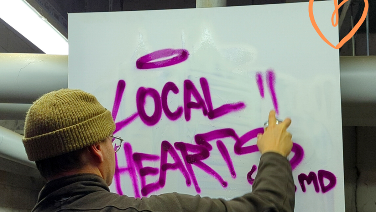 Digitales Engagement bei Local Hearts Magdeburg - Ein Mann besprüht ein Plakat mit Schrift "Local Hearts"