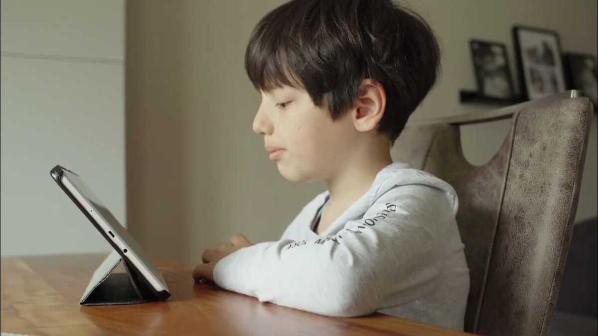 Ein Kind sitzt vor einem Tablet und schaut interessiert drauf